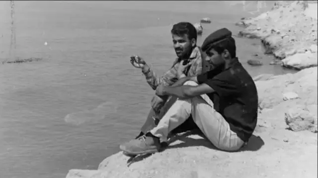 غلامحسین ساعدی و ناصر تقوایی روی یک صخره کنار ساحل جنوب ایران نشسته‌اند.