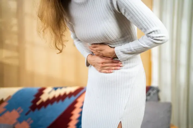 Karnını tutan bir kadın