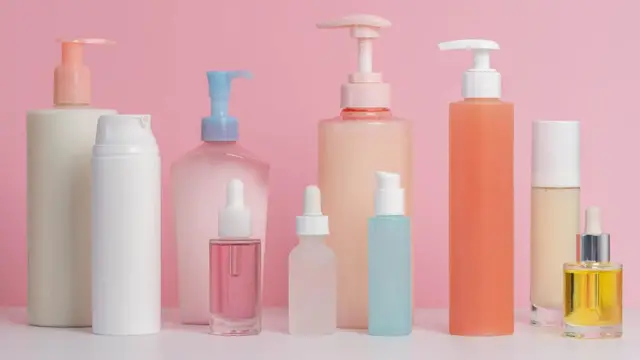Frascos variados de produtos de skincare sobre fundo rosa.
