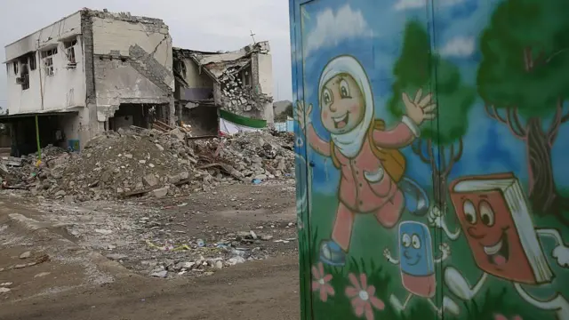 Ruinas de una escuela con un mural con dibujos infantiles