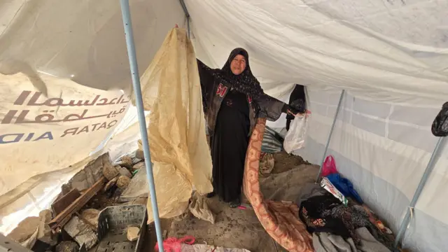 سيدة فى إحدى الخيام ترفع مرتبة نوم وأكياس بلاستيكية تظهر تحتها مياه الأمطار