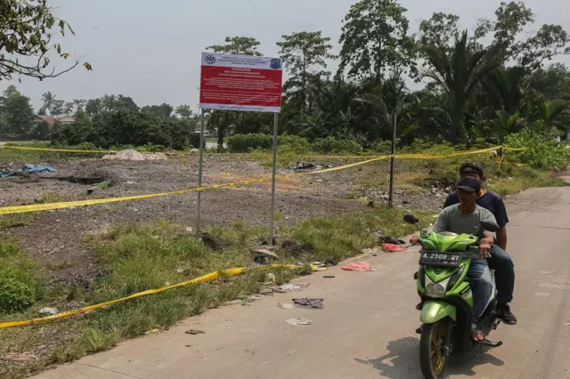 Dua pria bersepeda motor melewati lapangan yang bertanda peringatan bahaya radiasi.