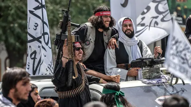 په کابل کې د طالبانو حکومت ځواکونه په یوه موټر کې لیدل کېږي چې وسلې ورسره دي او تر شا یې د طالبانو حکومت بیرغونه هم برېښي. 