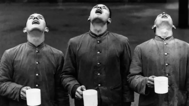 ثلاثة رجال يحملون أكواباً ويقومون بعملية الغرغرة لتنظيف أفواههم