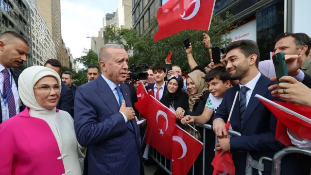 Erdoğan barikat arkasında Türk bayrağı tutan insanları selamlıyor. Yanında Emine Erdoğan var.