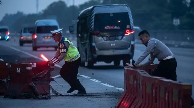 Polisi Lalu Lintas mendorong pembatas jalan menjelang pemberlakuakn contraflow di kawasan Gerbang Tol Cikampek Utama, Karawang, Jawa Barat, Jumat (5/4/2024).