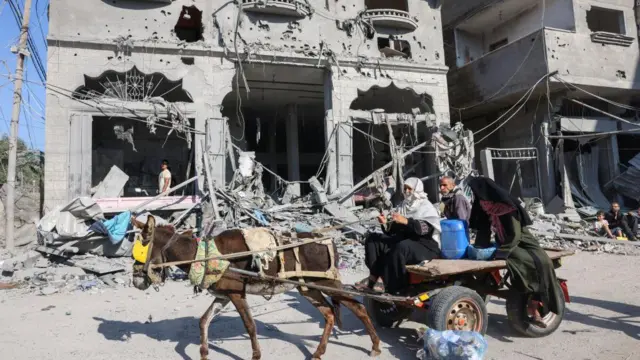 Warga Palestina mengemudikan kereta kuda di tengah reruntuhan bangunan yang hancur akibat serangan udara Israel di Rafah, Jalur Gaza selatan, Kamis (12/10).