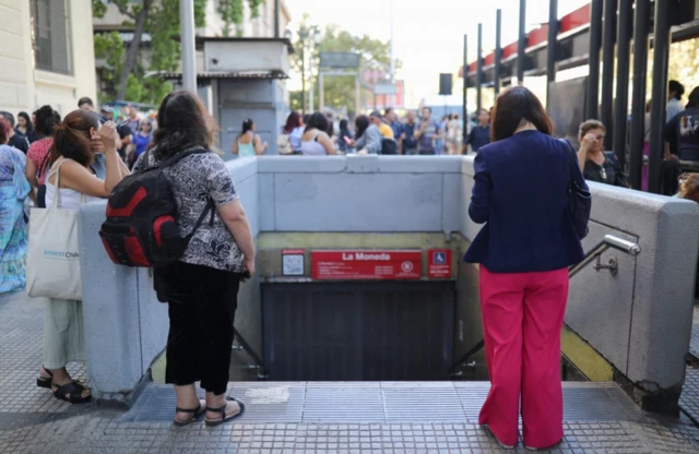 Personas esperando cerca de una boca de metro en Santiago