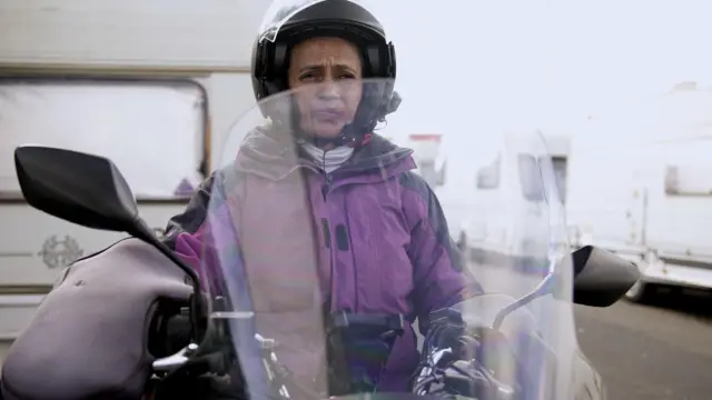 Célia Campos embet23moto, paradabet23frente ao trailer onde mora