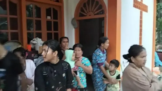 Sejumlah orang sedang dalam keadaan panik berdiri di depan gereja.