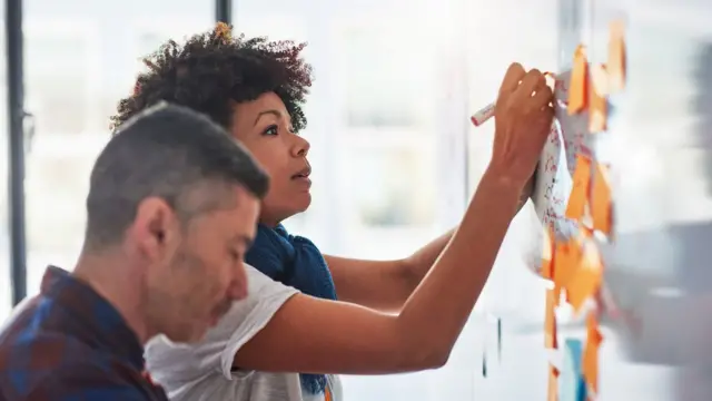 Una pareja de personas trabajando en una pizarra.