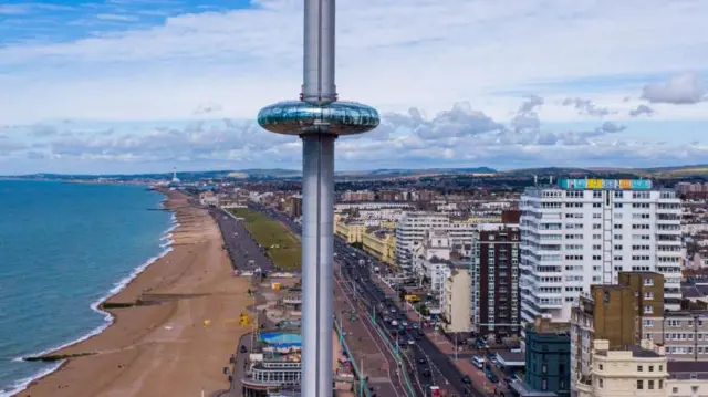 The i360 tower with its viewing platform in the air. The shore of Brighton beach is in the background. 