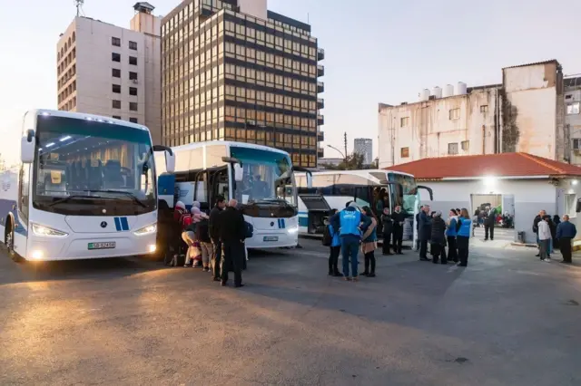 لاجئون سوريون يستقلون حافلات متجهة إلى سوريا في محطة حافلات في العاصمة الأردنية عمّان، بحضور مسؤولي المفوضية