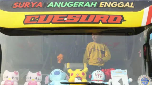 Seorang anak terlihat di depan bus yang akan mengantarkannya dan keluarga serta ratusan pemudik menuju kampung halaman mereka menjelang liburan Idul Fitri Muslim di terminal bus Pondok Cabe di Tangerang Selatan, Banten, Senin (17/04).