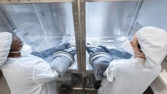 นักวิทยาศาสตร์ถอดเอาปลอกชั้นนอก ซึ่งครอบรักษาความปลอดภัยให้หลอดเก็บตัวอย่างออกก่อน