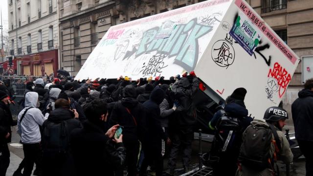 Demonstrators overturn a container during a demonstration against the pension overhauls, in Paris, on 5 December, 2019.