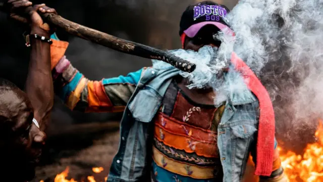 A man holds a burning stick as opposition supporters demonstrate at a burning barricade in Kibera, Nairobi, 25/10/2017