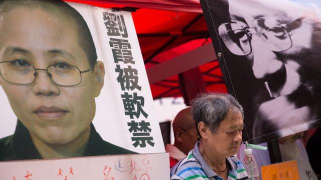 A man observes a minute of silence between photos of late Chinese dissident and Nobel Price recipient Liu Xiaobo (R) and his wife Liu Xia (L) in a booth set up by supporters in Hong Kong, China, 10 July 2018.