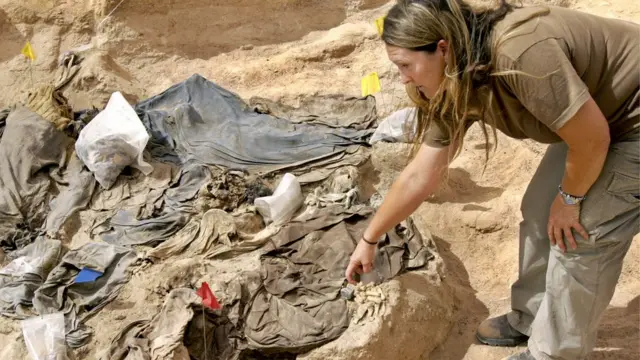 یک متخصص پزشکی قانونی در یک گور کشتار جمعی در جنوب عراق استخوان‌ها و لباس‌های قربانیان را آزمایش می‌کند