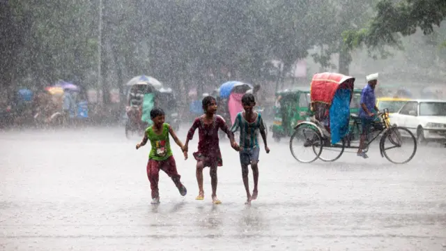 তিনটি ছোট ছোট ছেলে-মেয়ে বৃষ্টিতে ভিজছে।