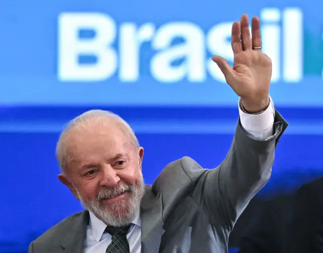 Lula acena com a mão e sorri