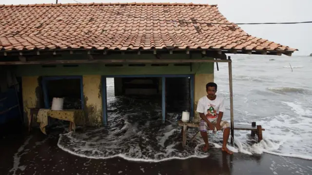 Seorang pria duduk di depan rumahnya yang hancur dan tenggelam akibat abrasi gelombang laut di pesisir utara kota Pekalongan, Jawa Tengah, pada 3 Juni 2021