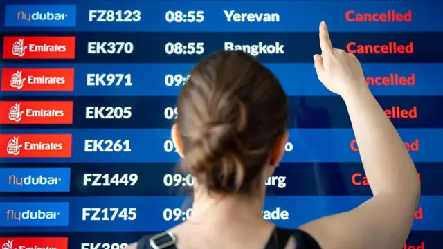 Женщина смотрит на табло международных рейсов в аэропорту Кракова