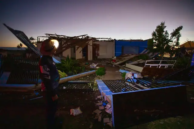 Casas destruídas e um homem olhando para destruição
