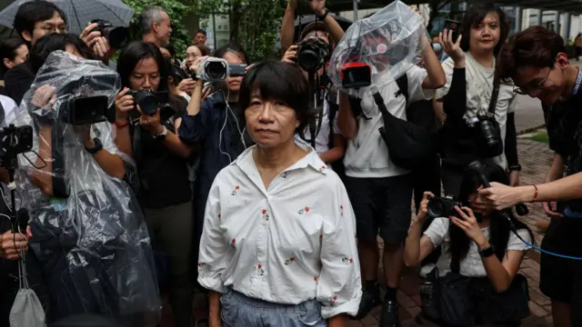 李卓人妻子邓燕娥(中)听判后离开法院时被记者包围拍摄(21/8/2026)