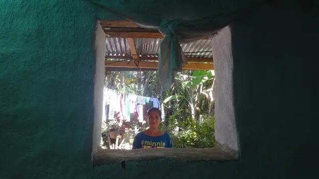 Una mujer mira desde afuera por la ventana hacia el interior de su casa recién pintada