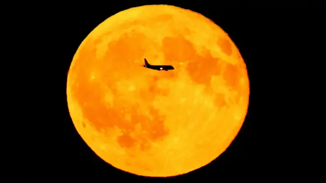 Putnički avion prolazi pored punog meseca iznad Frankfurta u Nemačkoj