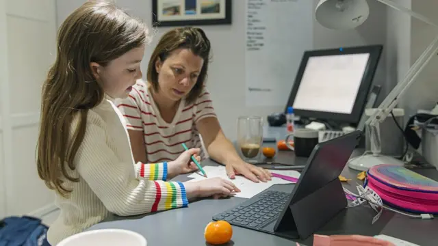 Mujer con una niña dando una explicación mientras trabaja de manera remota.