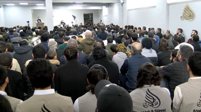 Ahlâk ve Sünnet dergisinin Ankara temsilciliğinin bir etkinliğinden bir kare. Kapalı bir mekanda bir kişi konuşuyor ve onlarca kişi yere oturmuş bir şekilde onu dinliyor. 