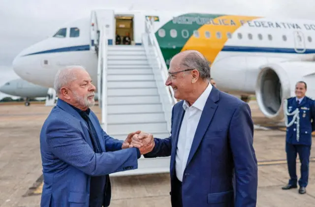 Presidente Lula segura a mão de seu vice, Geraldo Alckmin, antes de embarcar para a China em abril de 2023.