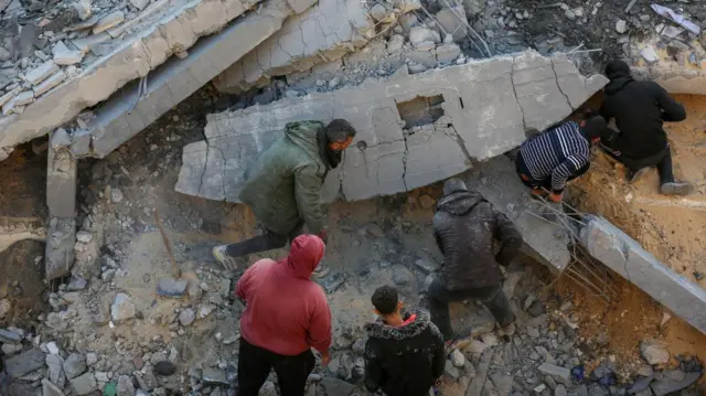 ग़ज़ा में एक घर पर हुए इसराइली हमले के बाद फंस गए रिश्तेदारों को तलाश करता परिवार