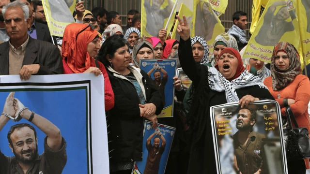 Filistinli eylemciler bayraklar ve El Fetih lideri Mervan Barguti'nin fotoğraflarıyla birlikte. 