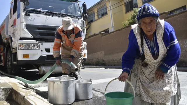 Mujer en Bolivia cargando agua de una cisterna en un balde en Bolivia
