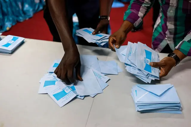 Les agents électoraux préparent les enveloppes de vote alors que le dépouillement commence au bureau de vote de l'école publique Bastos à Yaoundé, le 12 octobre 2025, après la clôture du scrutin pour l'élection présidentielle au Cameroun.