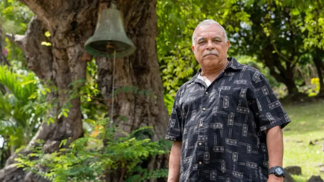 D. C. Campbell ao lado do sino que chamava os trabalhadores escravizados na fazenda Belmont, em Granada