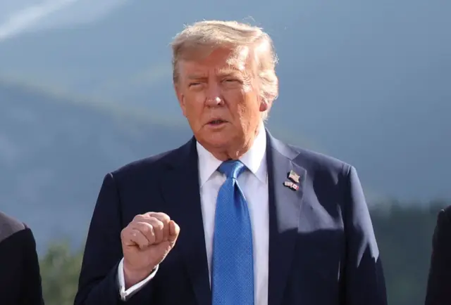 Trump posando para foto, em pé, com feição séria