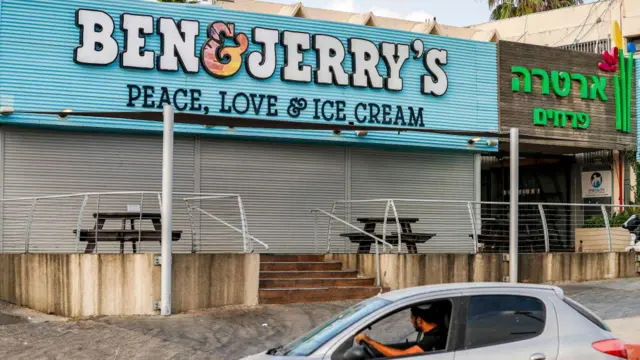 Автомобилист проезжает мимо закрытого магазина мороженого «Ben & Jerry's» в израильском городе Явне, примерно в 30 километрах к югу от Тель-Авива. В здании опущены решетки, закрывающие окна