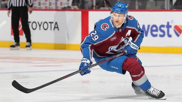 Канадский нападающий в форме клуба НХЛ "Колорадо Эвеланш" Натан Маккиннон на льду с клюшкой закладывает вираж