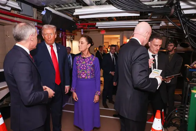Carney, Trump y Sheinbaum están detrás del escenario durante el evento de la FIFA que se ofició en diciembre. Carney está hablando mientras Trump y Sheinbaum lo miran con atención.