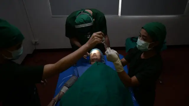 หลังเข้าห้องผ่าตัด ขั้นตอนแรกคือการที่แพทย์จะฉีดยาชาให้กับเธอ โดยเหตุผลที่ไม่ใช้ยาสลบ เพราะต้องการให้คนไข้มีสติและสามารถลุกนั่งแล้วลืมตาได้ทันที หลังผ่าตัด เพื่อประเมินตาว่าเท่ากันหรือไม่