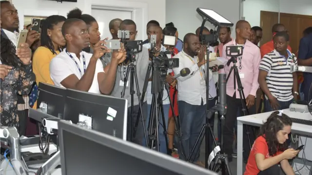 Awọn oniroyin duro pẹlu irinsẹ iyaworan ati igbohunsilẹ wọn