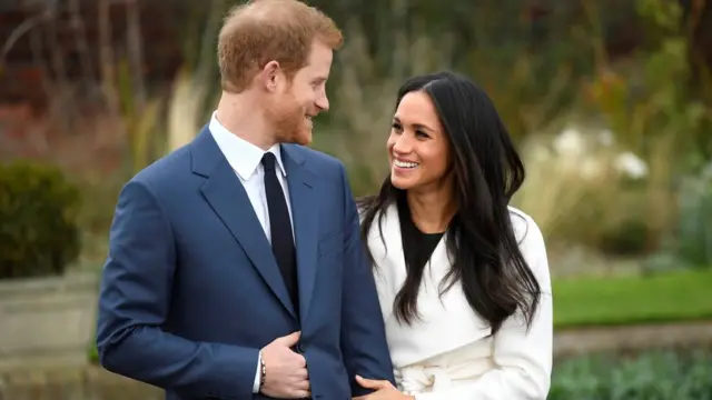 Harry e Meghan Markle sorrindo e olhando um para o outro,bet game 365um jardim