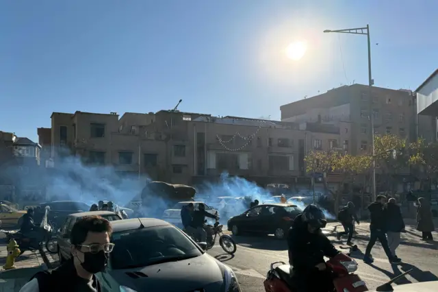 Fumaça nas ruas de Teerã enquanto pessoas protestam usando máscaras após a queda no valor da moeda iraniana
