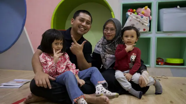 Rakean Andana duduk bersila di samping Nadia Calista. Putri mereka duduk di pangkuan Rakean, sementara putra mereka di pangkuan Nadia. Mereka semua berpose dan tersenyum untuk foto keluarga.