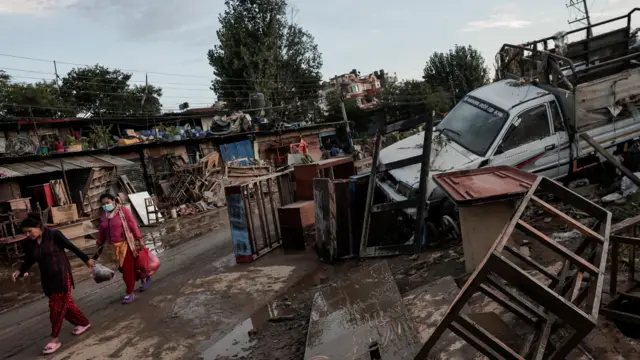 काठमाण्डूमा अविरल वर्षाका कारण प्रभावित क्षेत्रमा हिँड्दै केही महिला 