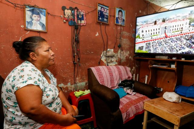 Mujer sigue la investidura de Nayib Bukele como presidente de El Salvador para un segundo mandato por la televisión el 1 de junio de 2024.